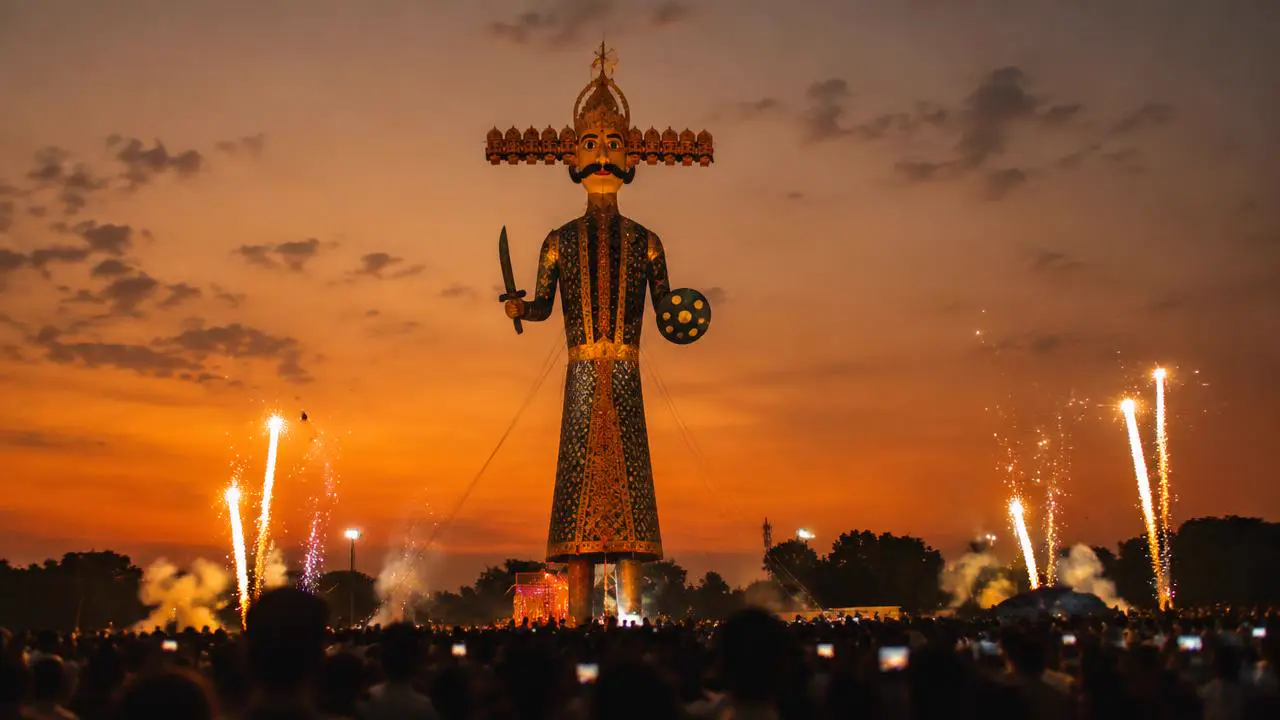 Tall Ravana effigy at dusk with fireworks on Dussehra